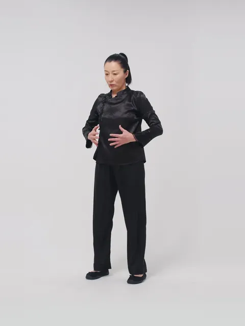 A woman standing with her hands on her belly, breathing slowly