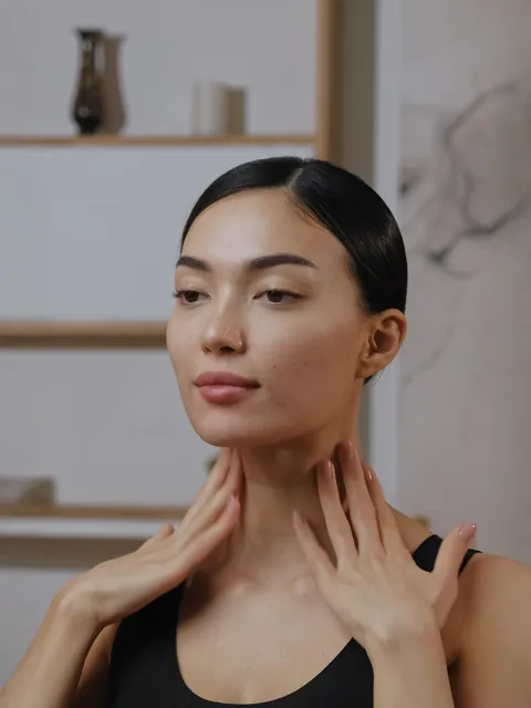 A woman gently massaging her neck during a face yoga routine