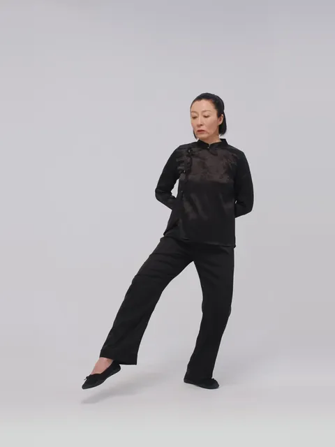 A woman stepping forward heel-first in walking tai chi