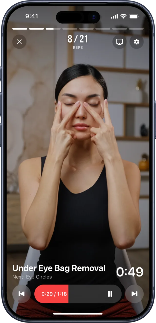 The Slimly player counting face yoga repetitions, 8 of 21, during Under Eye Bag Removal: a woman with her eyes closed, fingertips pressed in a V under her eyes