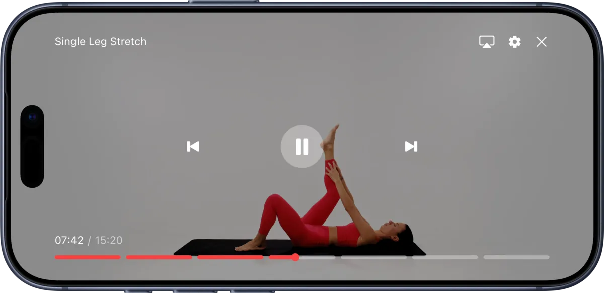 The Slimly player on a phone turned sideways during a mat pilates session: a woman lying on a mat, holding one leg up in a stretch
